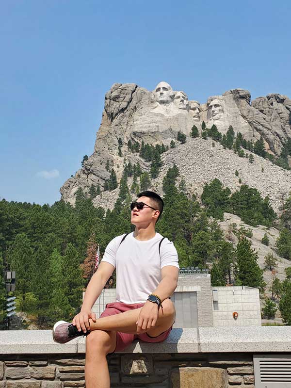 Aofei Mao poses in front of Mount Rushmore National Monument