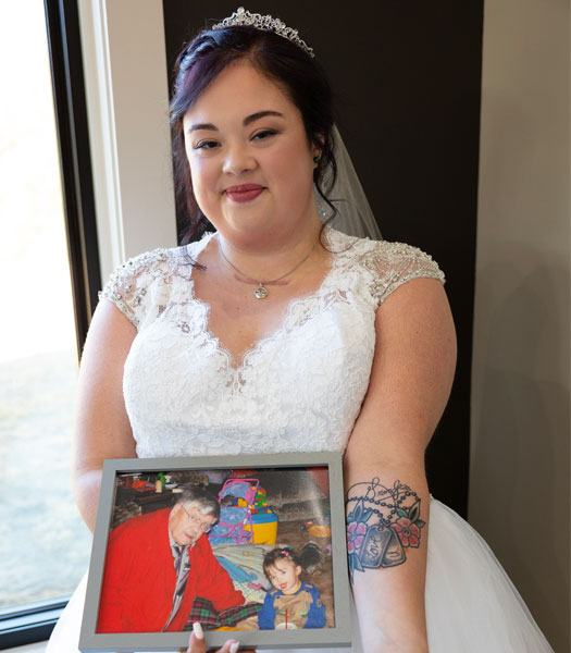 A picture of Aspen in a wedding dress holding an image of her grandfather who greatly impacted her life and who she is.