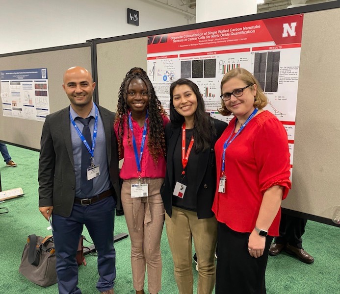 Dr. Iverson, Omer, Portia, and Ivon at BMES in front of Portia's Poster titled 'Organelle Colocalization of Single Walled Carbon Nanotube Sensors in Cancer Cells for Nitric Oxide Quantification'. 