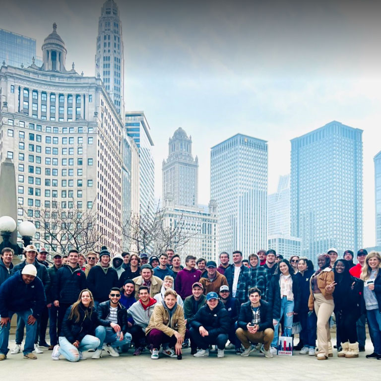 A group of Durham School students on a trip to Chicago take a photo with the skyline behind them.