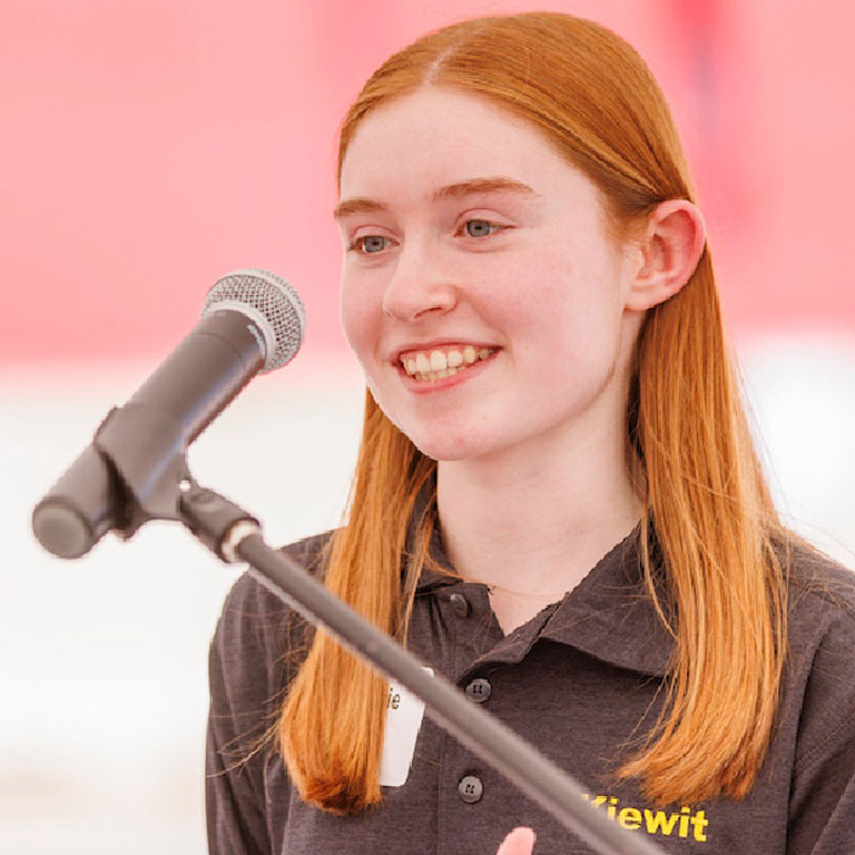 Young woman speaking at a podium.