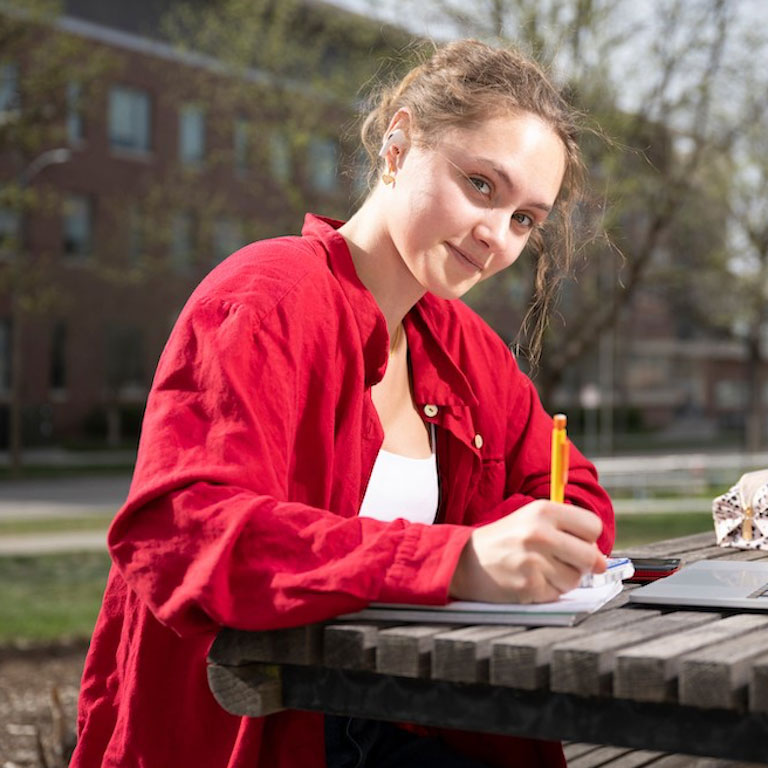 Student sitting at a picnic table outside studying.