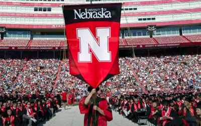 Person holding a Nebraska banner walks down the aisle inside Memorial Stadium at the 2022 Spring Commencement.