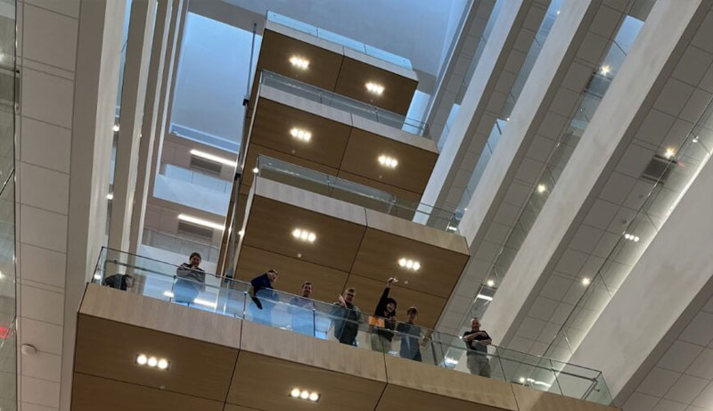 Students stand on the Kiewit Hall staircase during a paper aircraft competition.