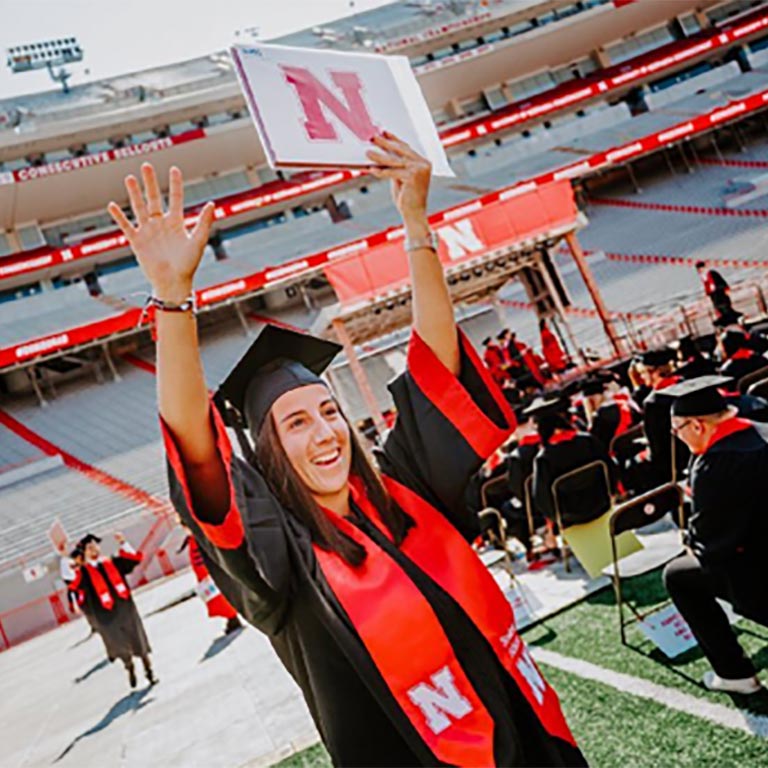 Student celebrates receiving her degree at commencement on the field at Memorial Stadium