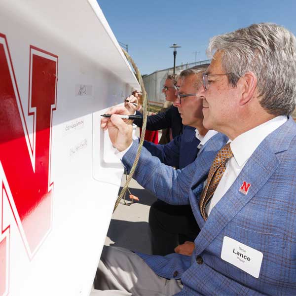 Lance C. Pérez (from right), dean of engineering, Chancellor Ronnie Green, and others sign the beam during the topping out ceremony at the Kiewit Hall site.