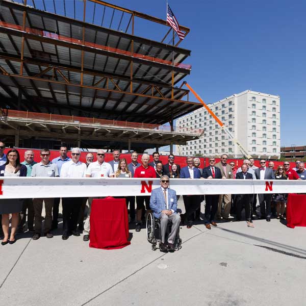 Group photo in front of the last beam being raised up atop Kiewit Hall.