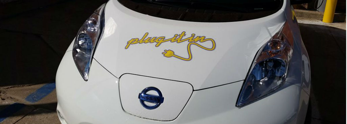 Car with 'Plug It In' written on the hood