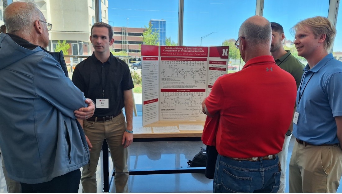 Group of people discussing a research poster in a bright indoor setting near a large window.