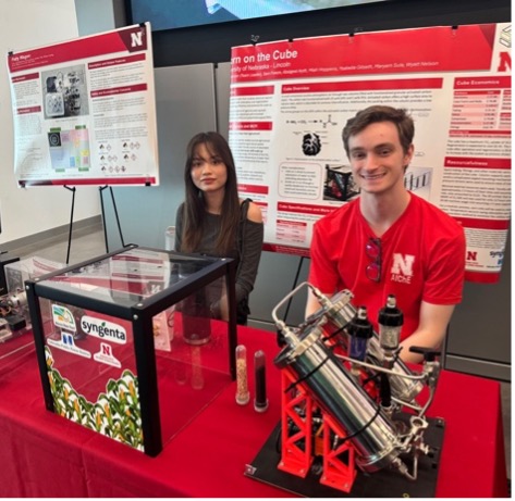 Two people behind a table displaying scientific equipment and research posters.