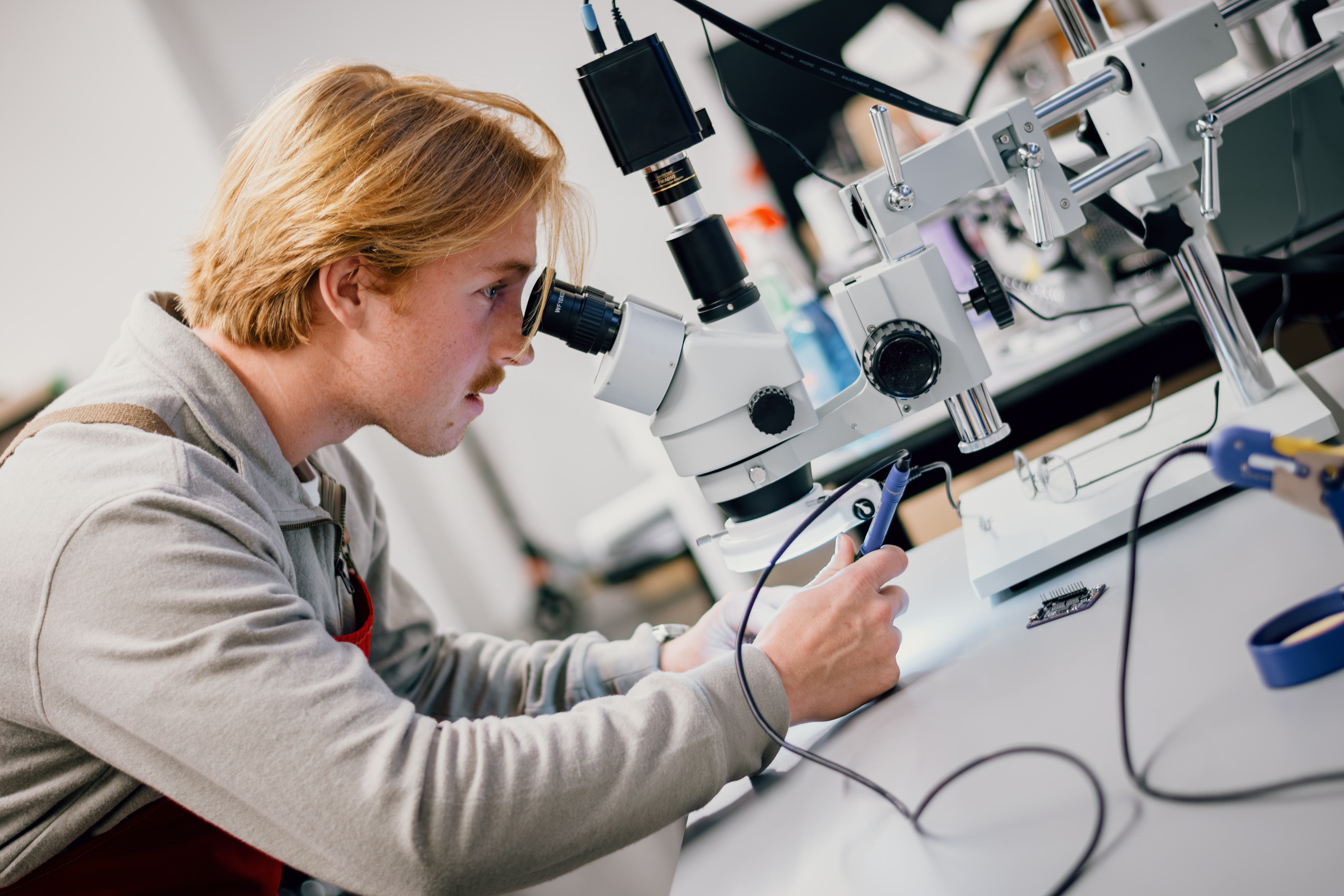 A student uses a microscope to aid in precision soddering.