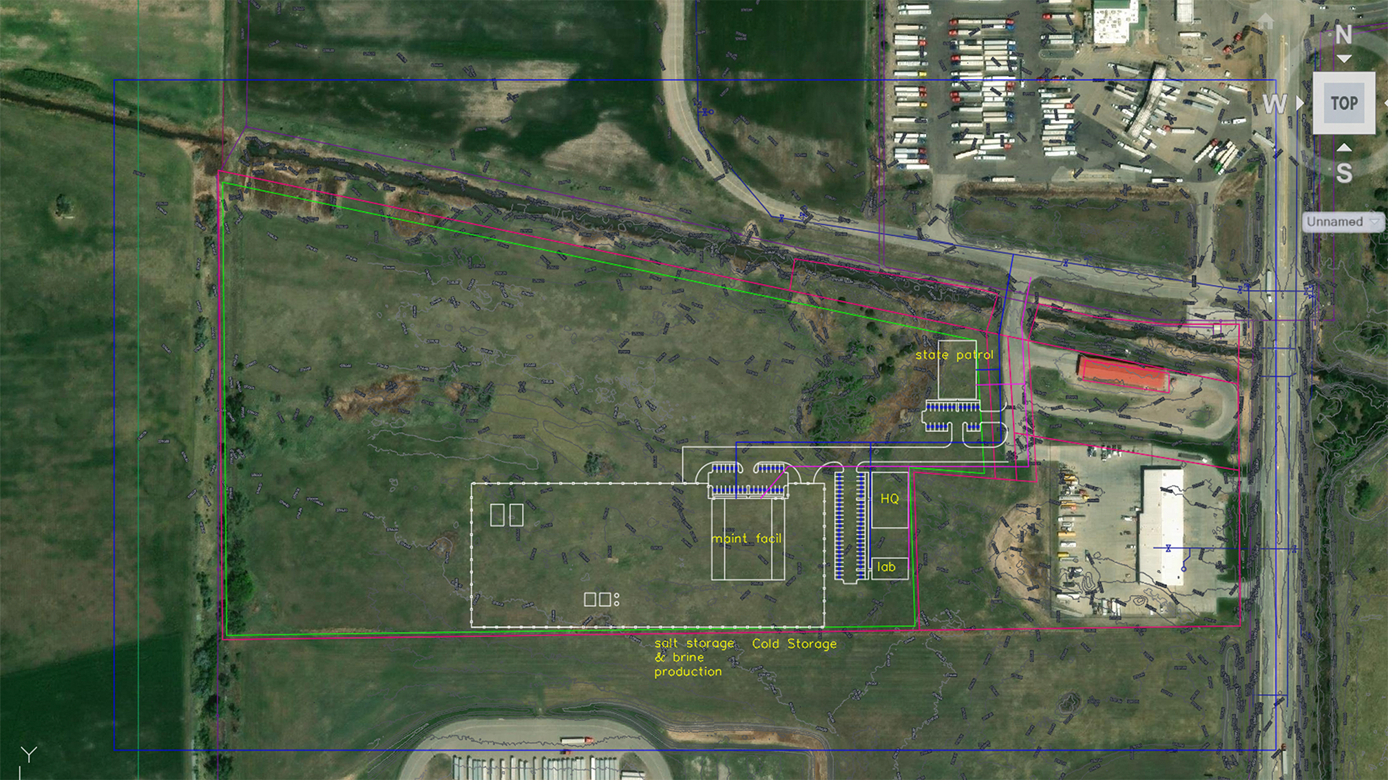 Aerial view of a facility layout plan surrounded by open green fields and industrial buildings.