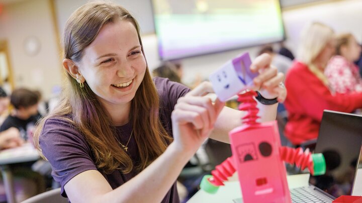 Bethany Miller, a junior hospitality, restaurant and tourism management major, works on a paper, vitamin-dispensing robot inside Howard L. Hawks Hall.