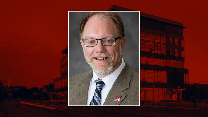 Blurred portrait over a red-toned building background.
