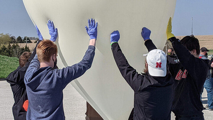 Members of the Big Red Satellite Team assist in the inflation of a high-altitude balloon in April 2021.