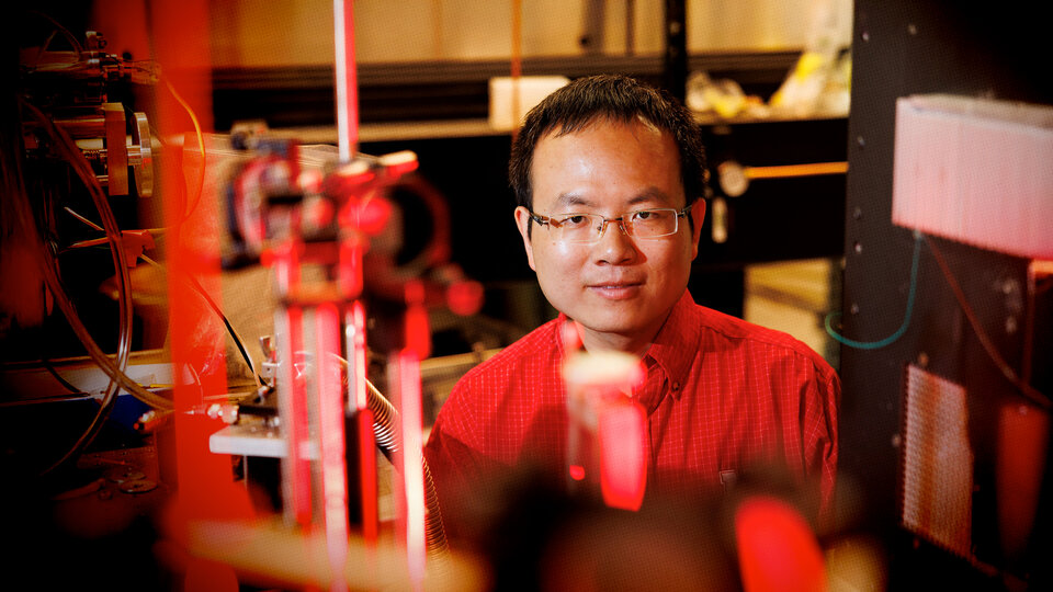 Laboratory setting with equipment and red lighting. Bai Cui, professor of Mechanical and Materials Engineering.