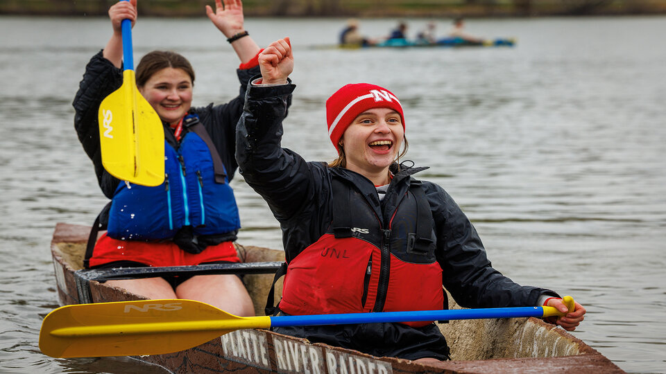 Two women navigate a concrete canoe on a Lincoln lake