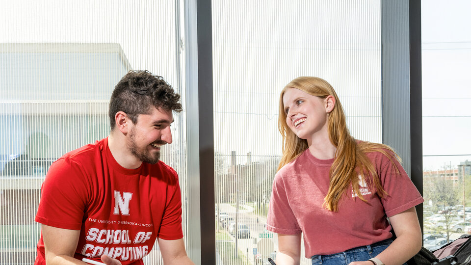 Two students sitting in Kiewit Hall and talking
