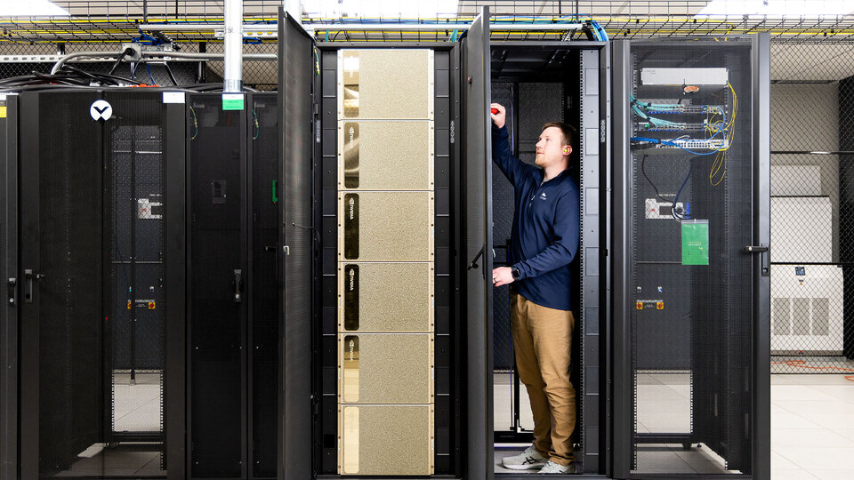 Man stands next to large computers 