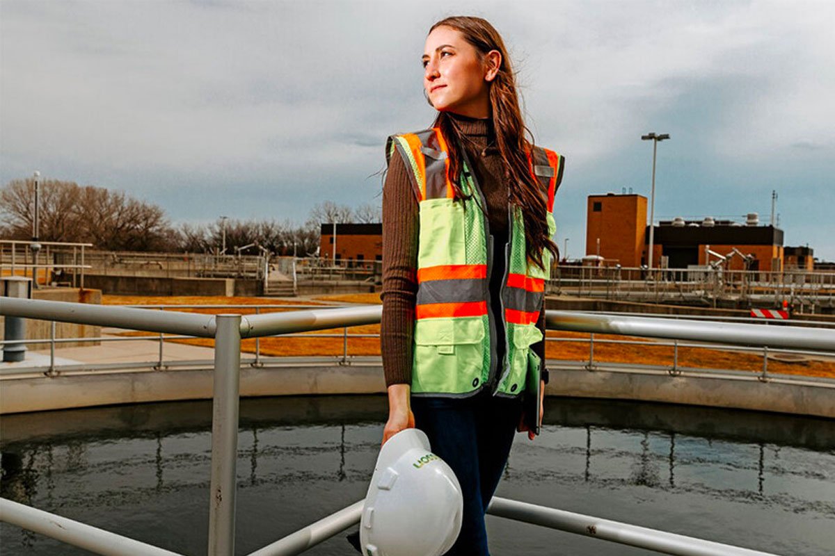Young woman in a construction vest stands on a work site
