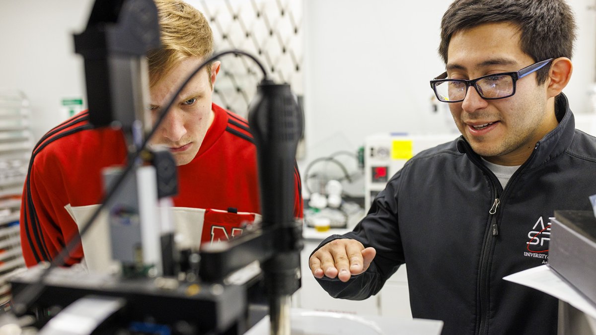 Two men working on a piece of equipment as part of the Aerospace Club design teams.