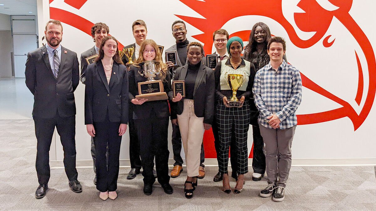 Students holding trophy as national champion debate team