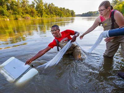 Seth Caines, Meredith Sutton and Moriah Brown stretch out to use a floating sieve to gather a water sample in the Elkhorn River on July 2. 