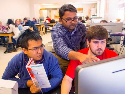 Santosh Pitla (Associate Professor of Biological Systems Engineering) working with two students in a computer lab.