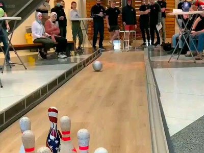 A bowling ball rolling down a lane towards the pins.