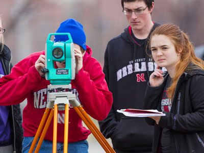 Students work with surveying equipment on campus