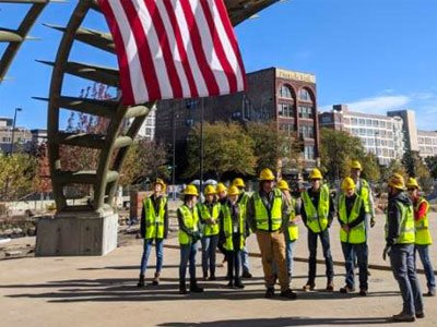 Students in construction hats and vests tour a park in Omaha