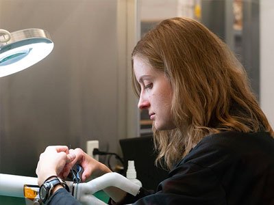 Woman works on a miniature robot used for surgical procedures